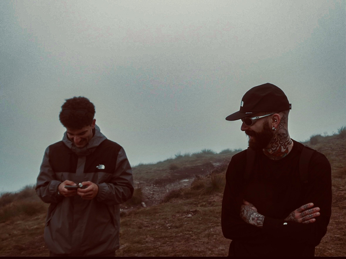 Two men standing in an open landscape