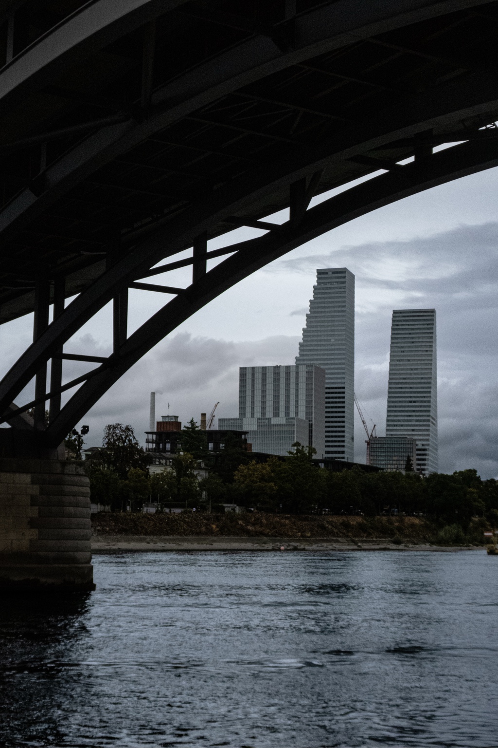 Basel skyline framed beneath the dark structure of a bridge